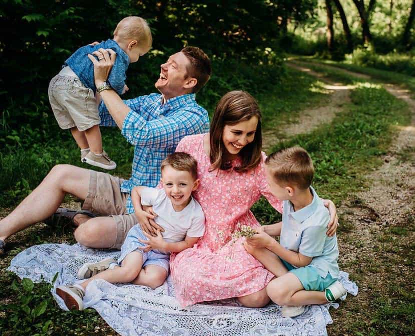 Family of 5 who love to travel sitting on blanket in a park