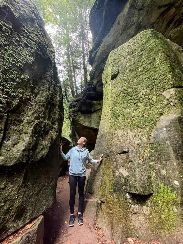 Woman standing between two huge rock formations in Hocking Hills