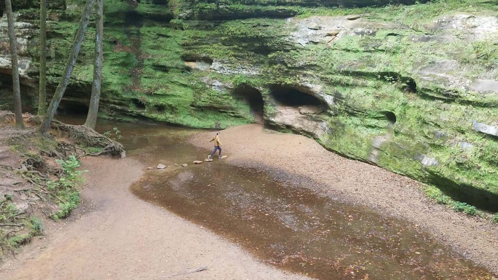 Woman walking on stepping stones across shallow creek in Hocking Hills State Park