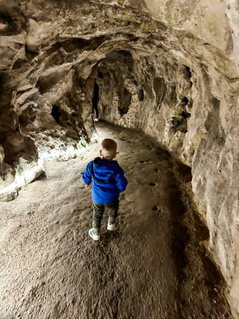 Little boy walking through underground tunnel after climbing down the Initiation Well at Quinta da Regaleira