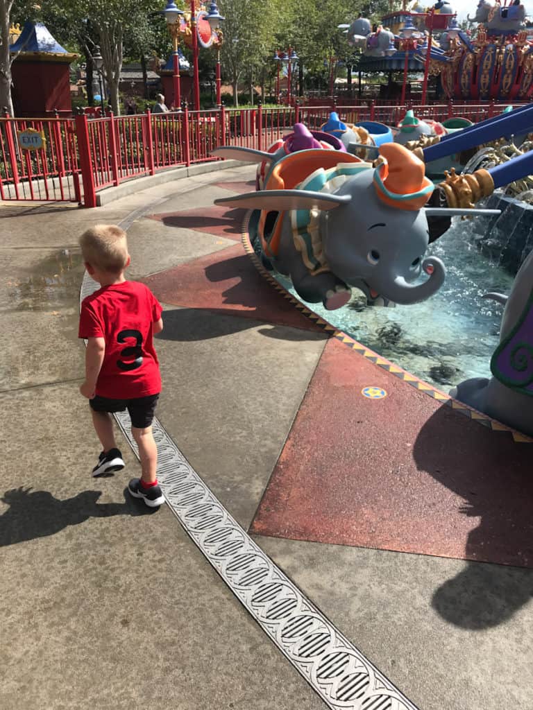Little boy running next to the Dumbo ride at Magic Kingdom in Walt Disney World