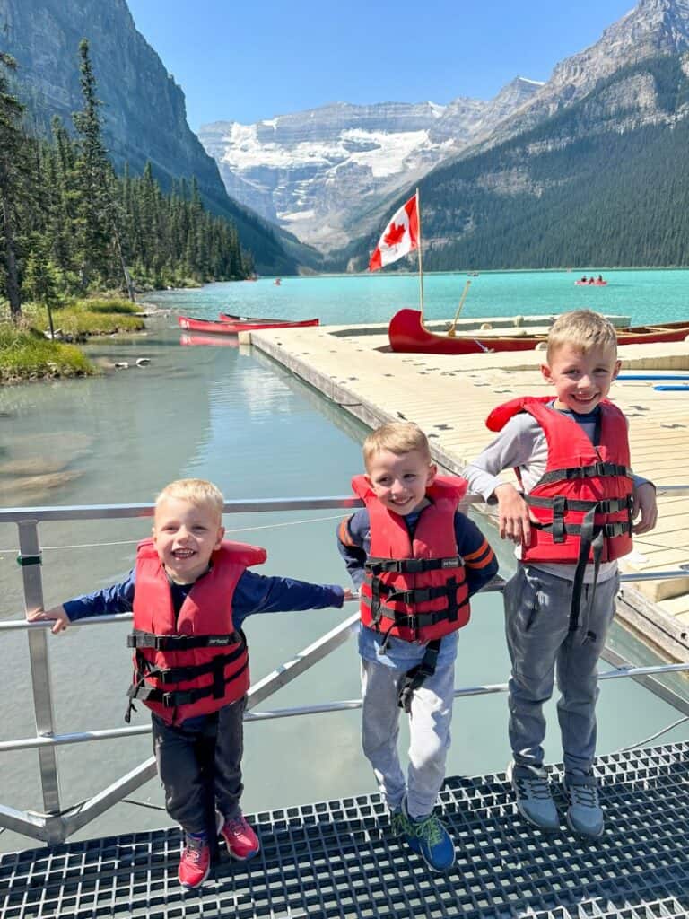 3 boys standing on dock waiting to canoe on Lake Louise