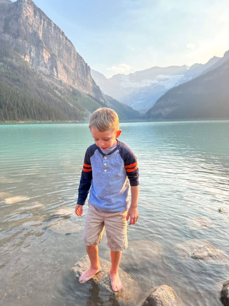 Boy standing on rock in Lake Louise, Banff with kids