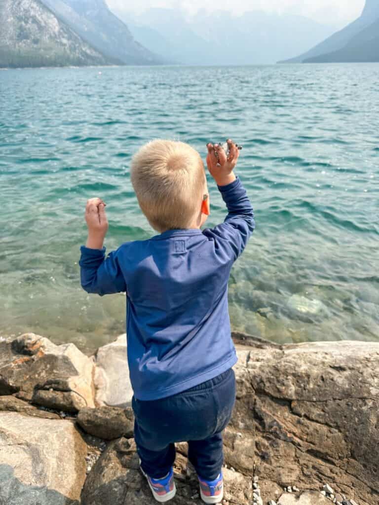 Banff with a toddler, boy throwing rocks in Lake Minnewanka