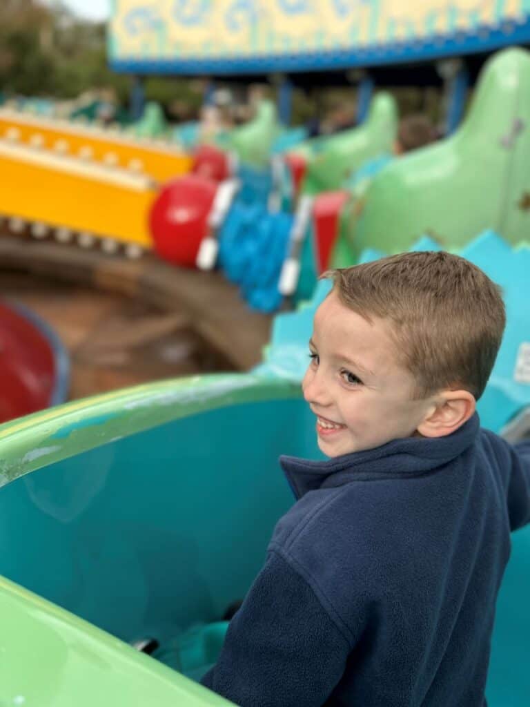 Toddler boy looking back and smiling while riding on TriceraTop Spin at Disney's Animal Kingdom